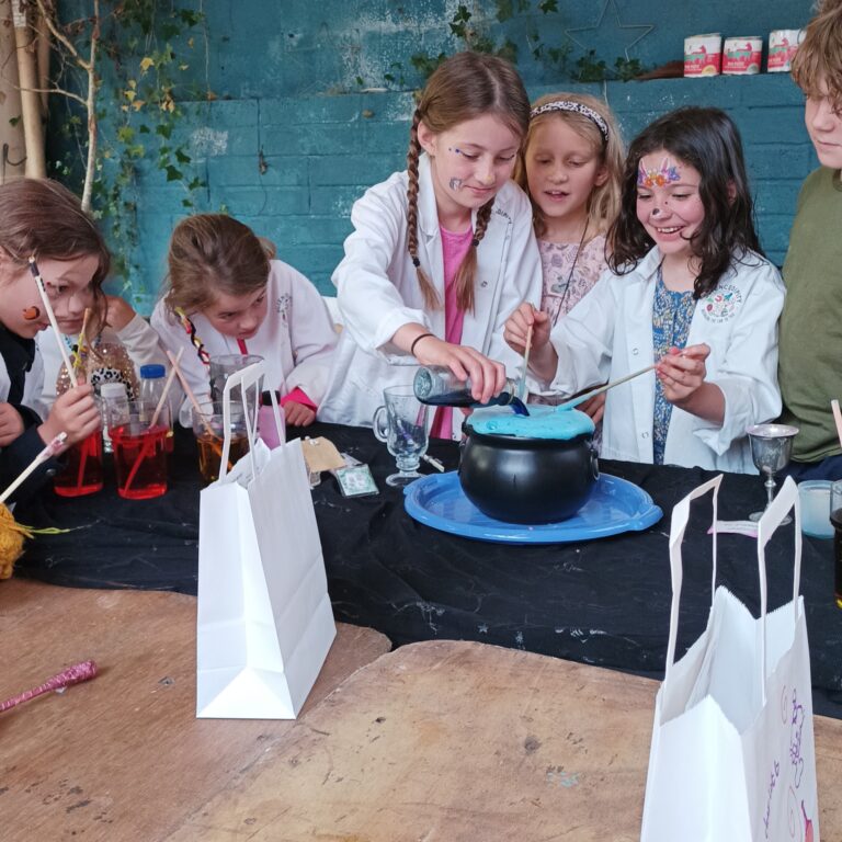 Children at our Magical potions party stirring a huge erupting potion in a cauldron
